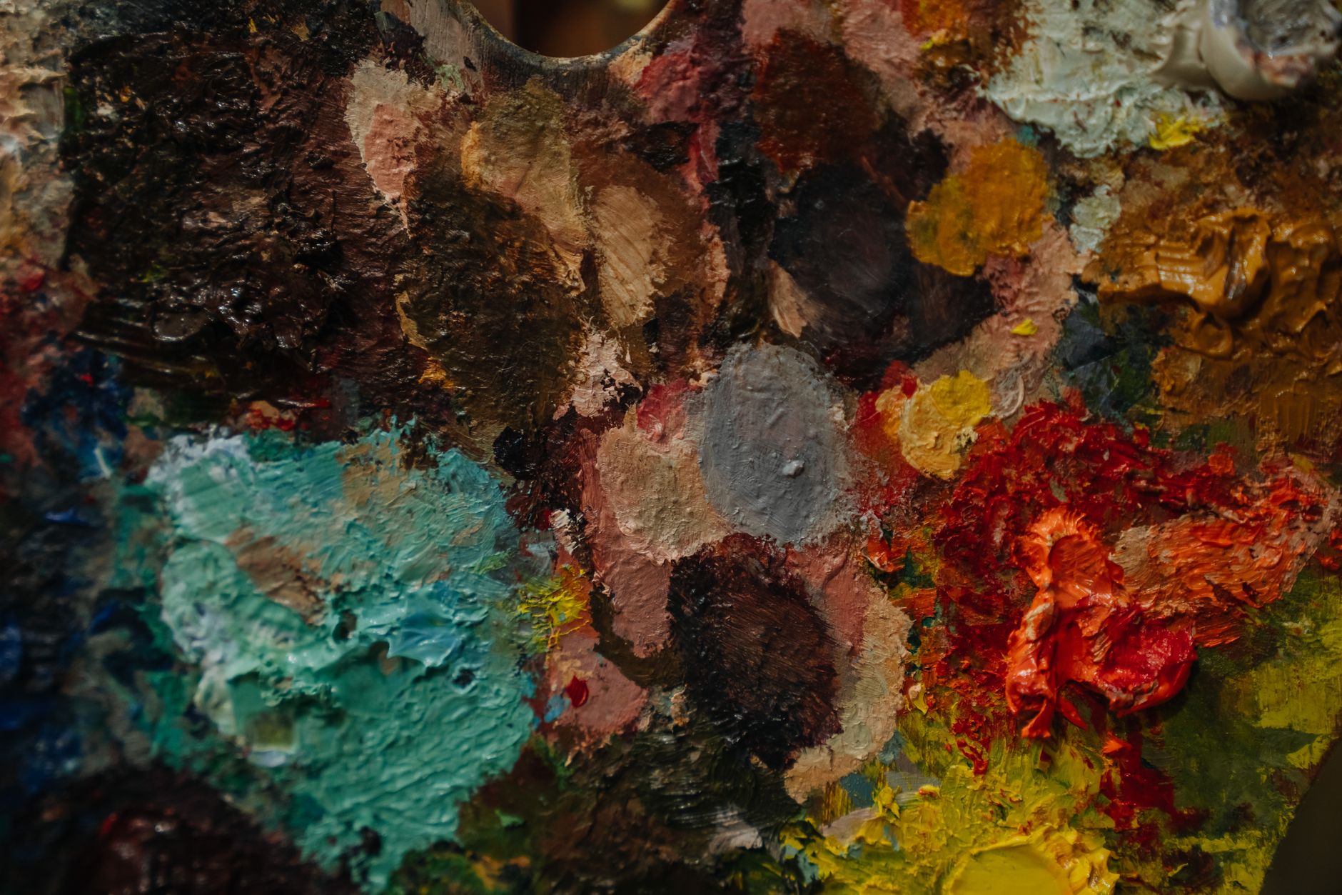 Close-up of a colorful artist's palette with various paint blobs and textures.